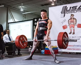 Powerlifter sumo deadlifting a barbell with weights.